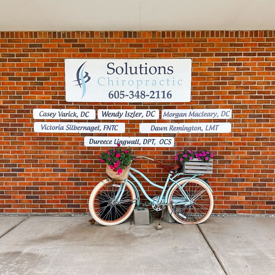 The Solutions Chiropractic sign and the bike with flower baskets outside the clinic